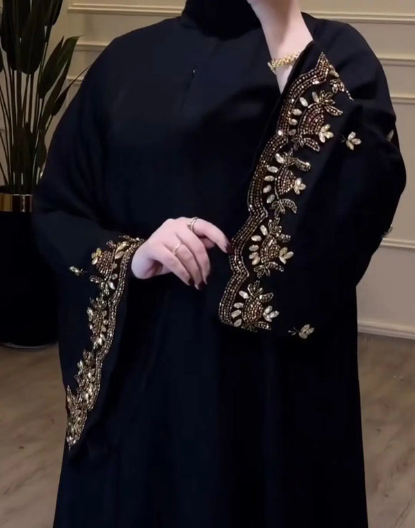 Elegant black abaya with gold embroidery along sleeves and neckline, with a zip worn by a model