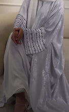 A woman wearing a sky blue flowy abaya, standing gracefully with a serene and modest look