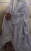 A woman wearing a sky blue flowy abaya, standing gracefully with a serene and modest look